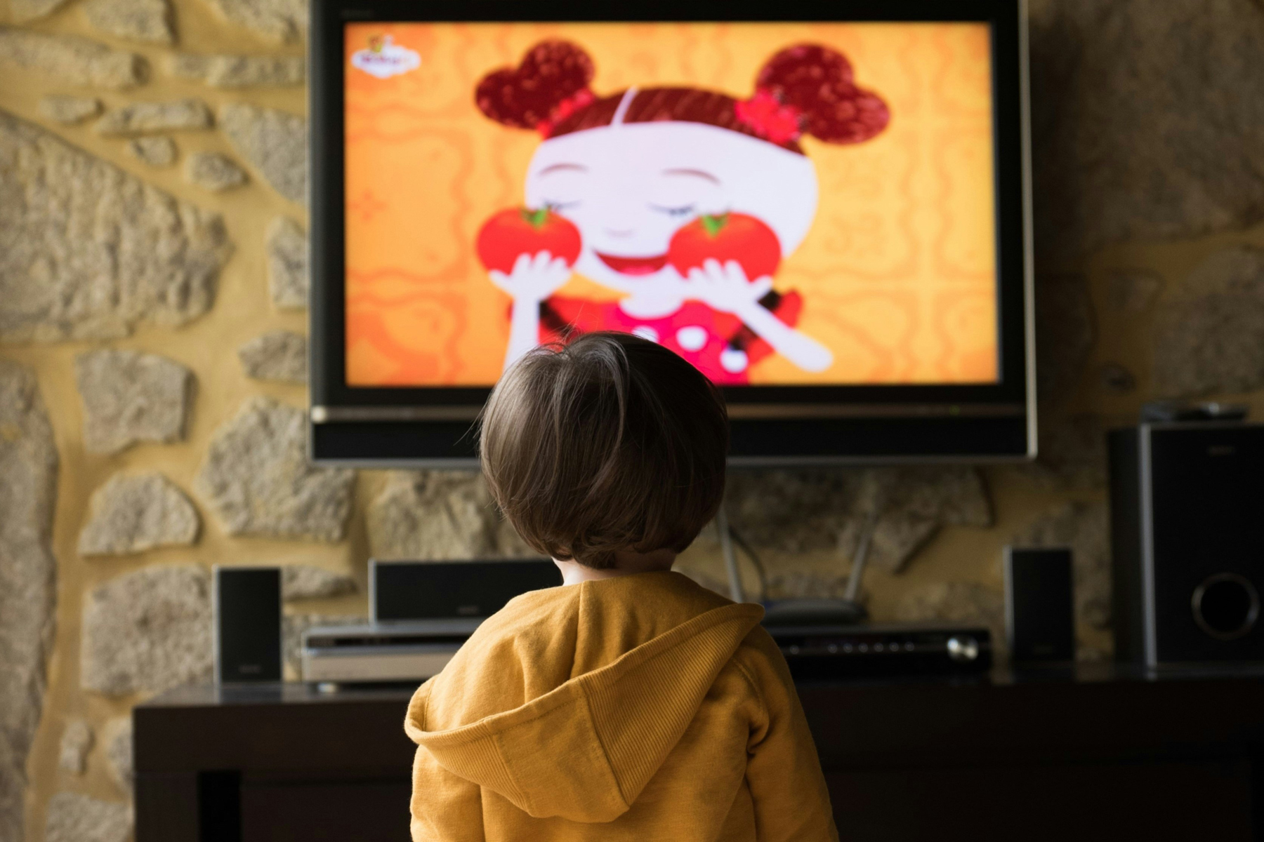 Kind fasst einen Fernsehbildschirm an